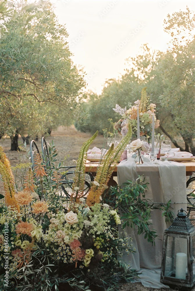 Outdoor wedding table setting among olive trees decorated with a wildflower centerpiece