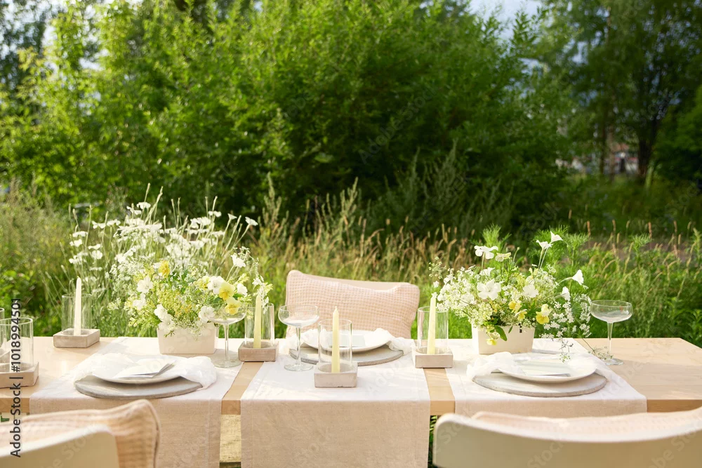 Outdoor table setting with white and yellow wildflower centerpieces and candles