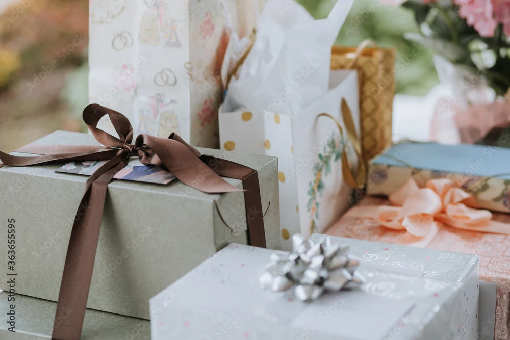Wrapped wedding gifts and gift bags with ribbons on a table