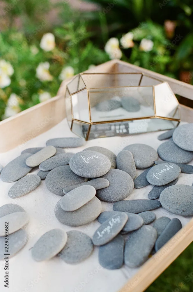 Engraved stones reading love, friends and loyalty displayed on a wooden tray