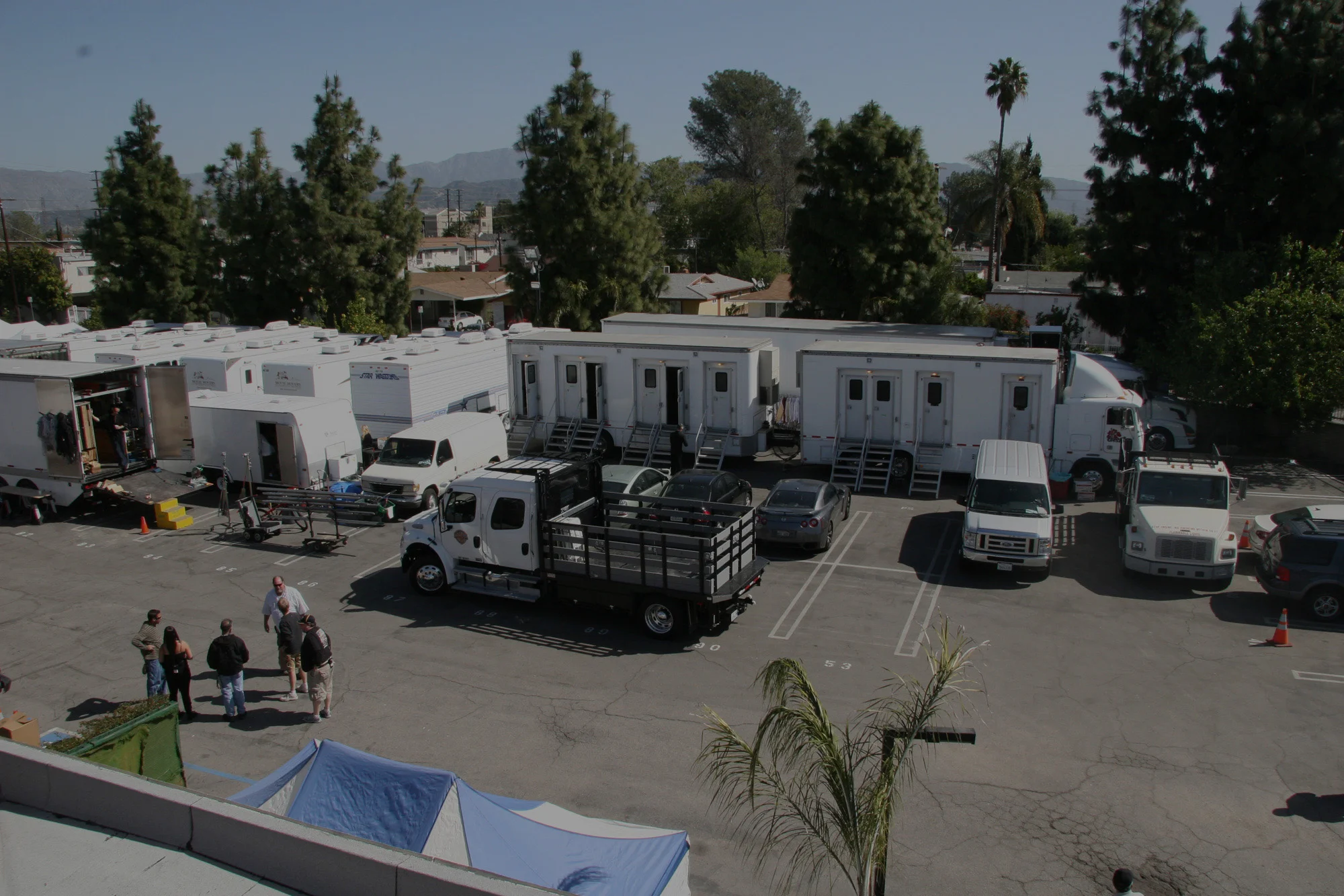 Film production trucks and trailers parked on location with mountains in the background