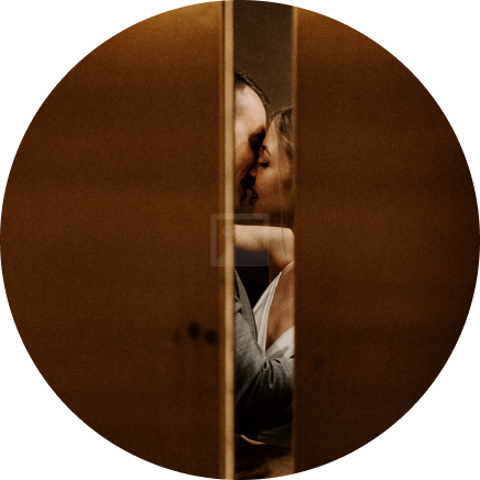Circular portrait of a couple kissing between wooden panels in warm light