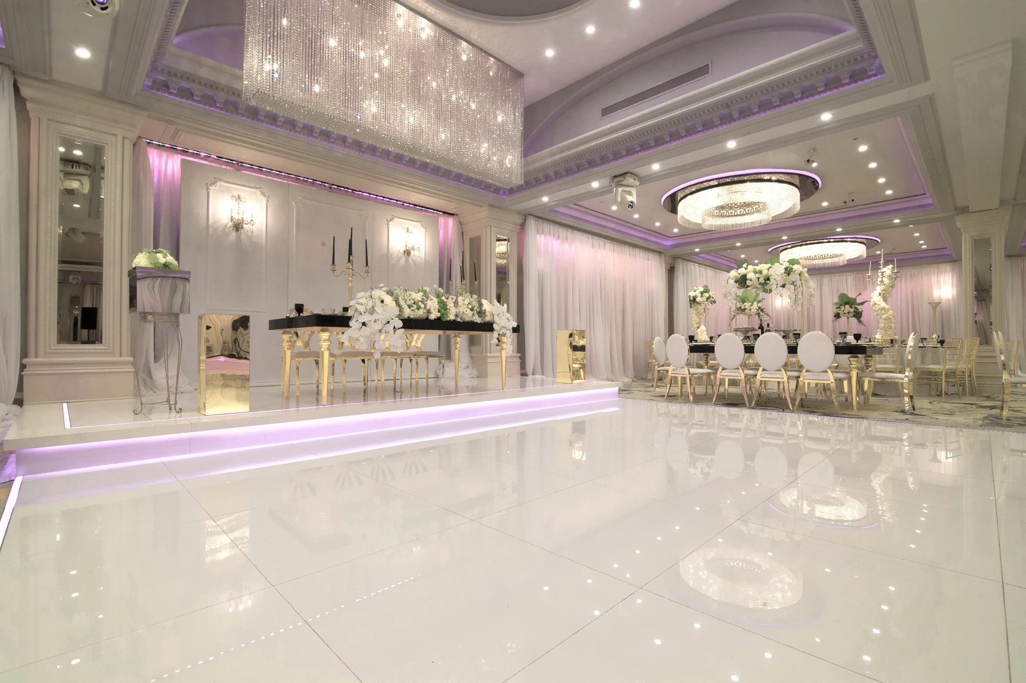 Glenoaks Ballroom reception space with purple lighting, crystal chandelier and a black sweetheart table