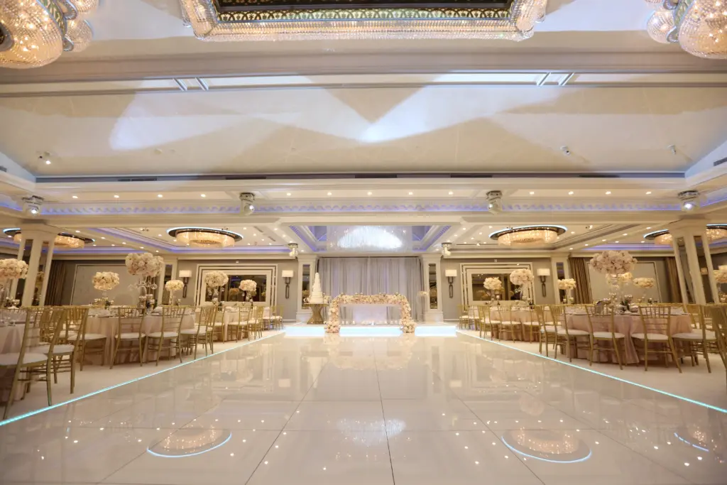 Glenoaks Ballroom set for a reception with a floral sweetheart table stage and gold chiavari chairs