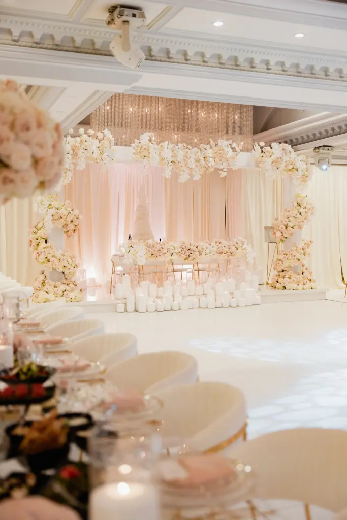 Glenoaks Ballroom floral arch and cake display with white lounge seating and candles