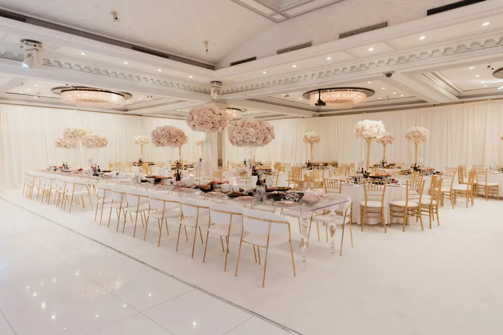 Glenoaks Ballroom set with a long guest table, gold chairs and hanging floral arrangements