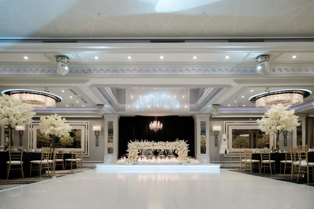 Glenoaks Ballroom reception with a white sweetheart table stage and gold chiavari chairs