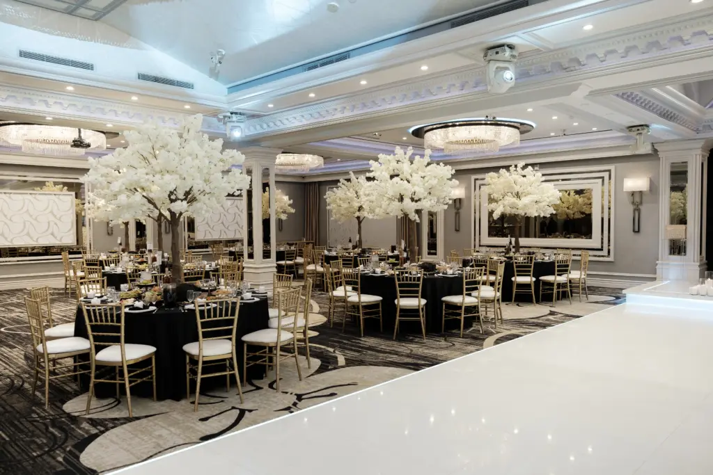 Glenoaks Ballroom set with white blossom tree centerpieces and black-linen round tables