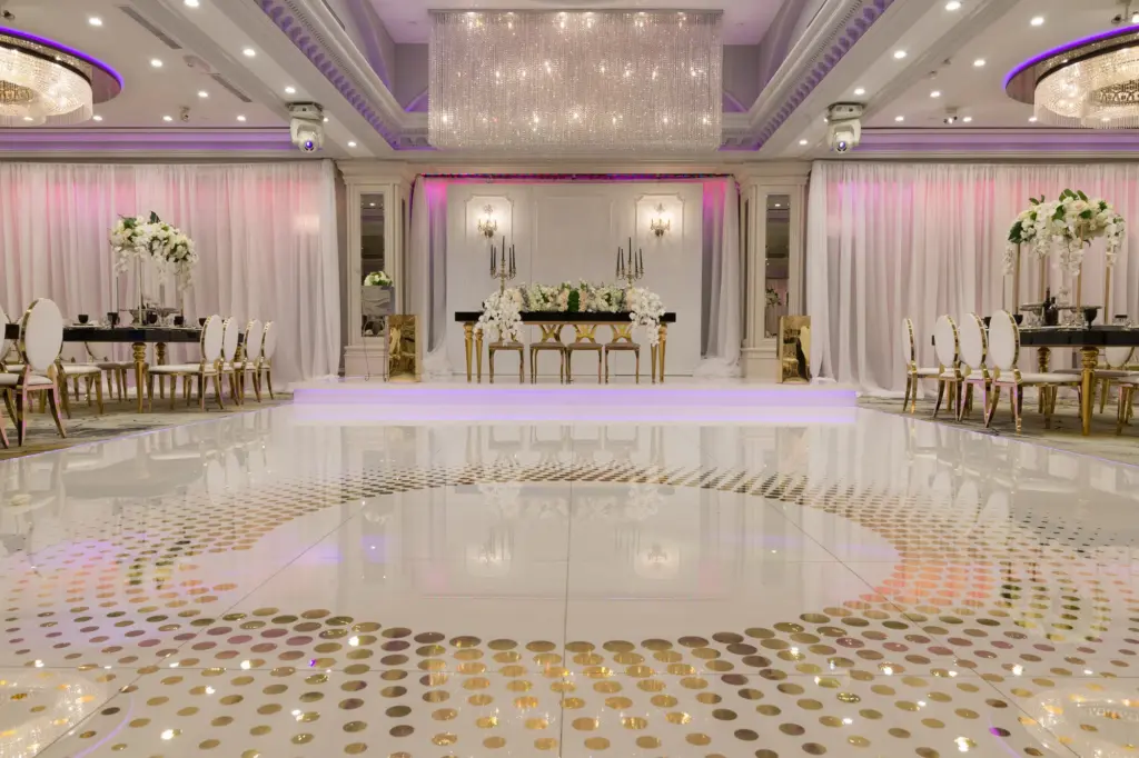 Glenoaks Ballroom stage with sweetheart table, crystal chandelier and patterned gold dance floor
