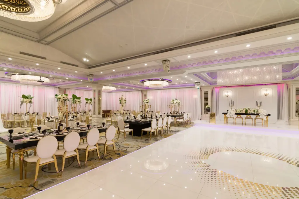 Glenoaks Ballroom set with round tables, gold chiavari chairs and purple uplighting