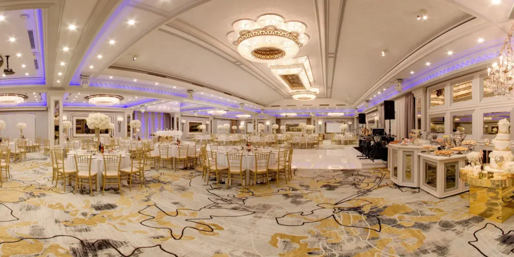 Panoramic view of Glenoaks Ballroom set with round tables, gold chairs and a dessert display