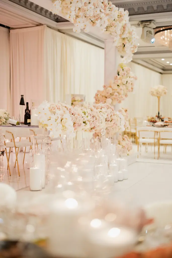 Close-up of a blush floral garland cascading over a candlelit reception table