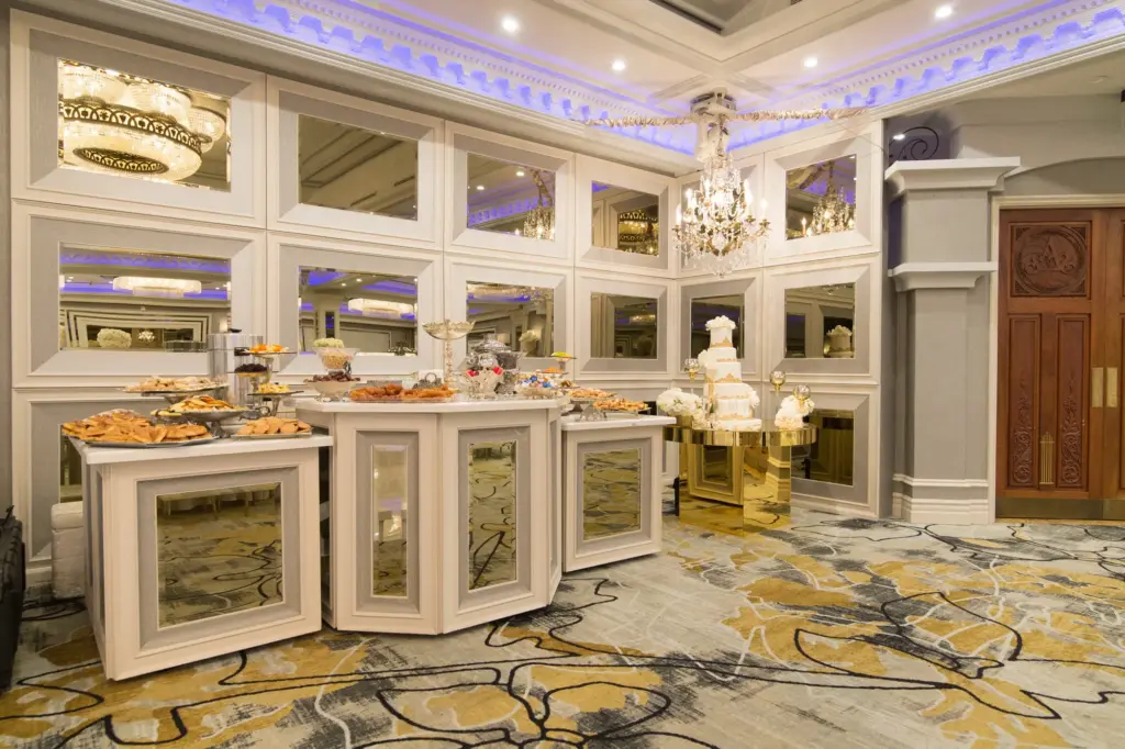 Dessert and pastry display station with mirrored cabinetry and a small wedding cake