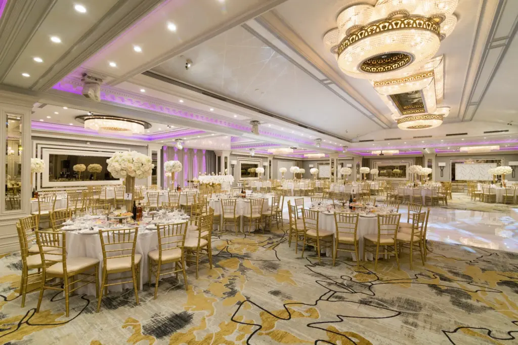 Glenoaks Ballroom dinner tables with tall white floral centerpieces and gold chiavari chairs