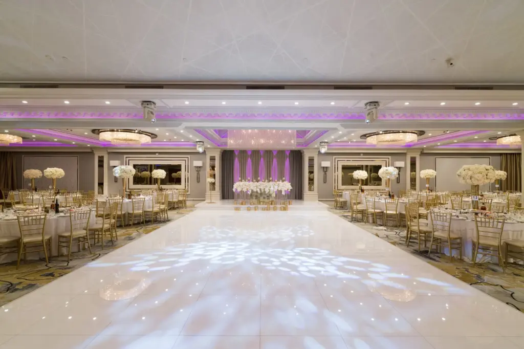 Glenoaks Ballroom dance floor and stage flanked by dinner tables under purple ambient lighting