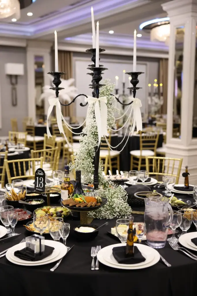 Black candelabra with baby's breath and pearl draping on a formal dinner table setting