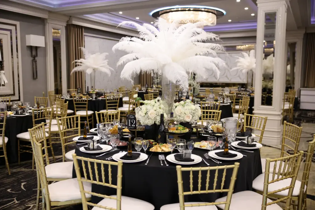 White ostrich feather centerpiece and place settings on a black-linen dinner table