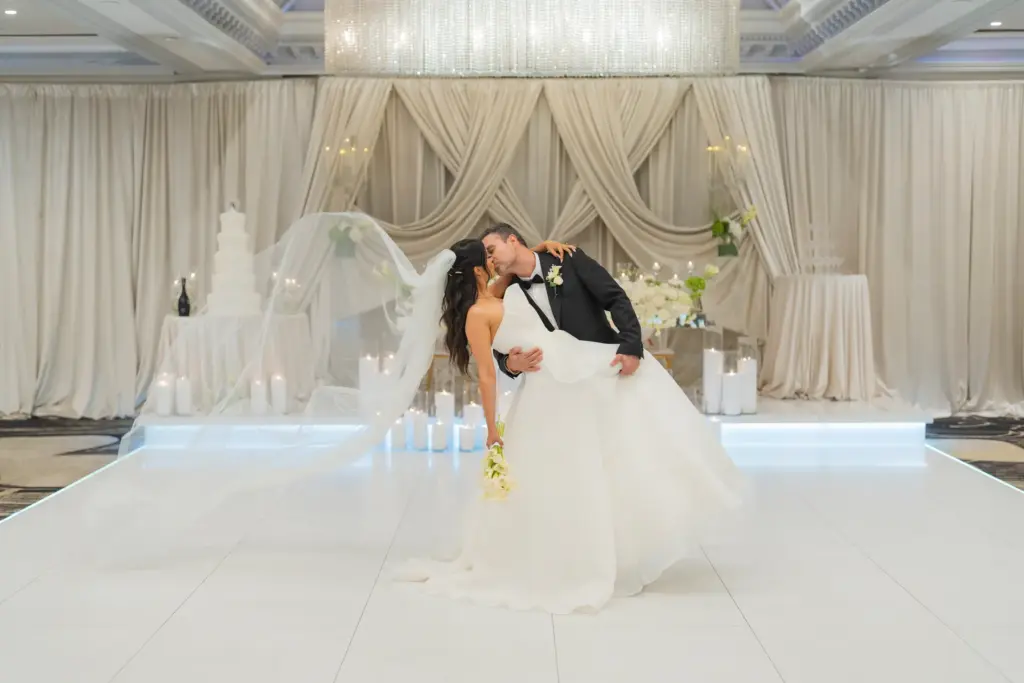 Bride and groom dancing on the reception floor with a flowing veil and candlelit backdrop