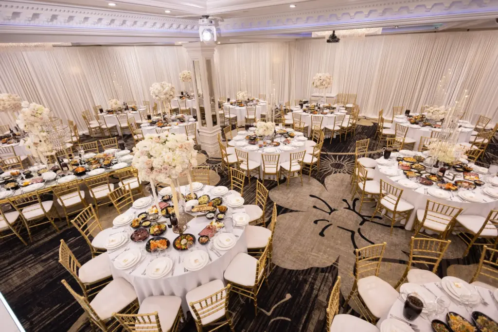 Elevated view of ballroom reception tables set with gold chiavari chairs and plated dinners