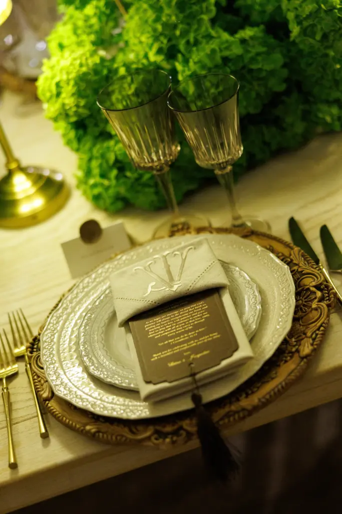 Elegant place setting with a monogrammed napkin, menu card and crystal glasses on a gold charger