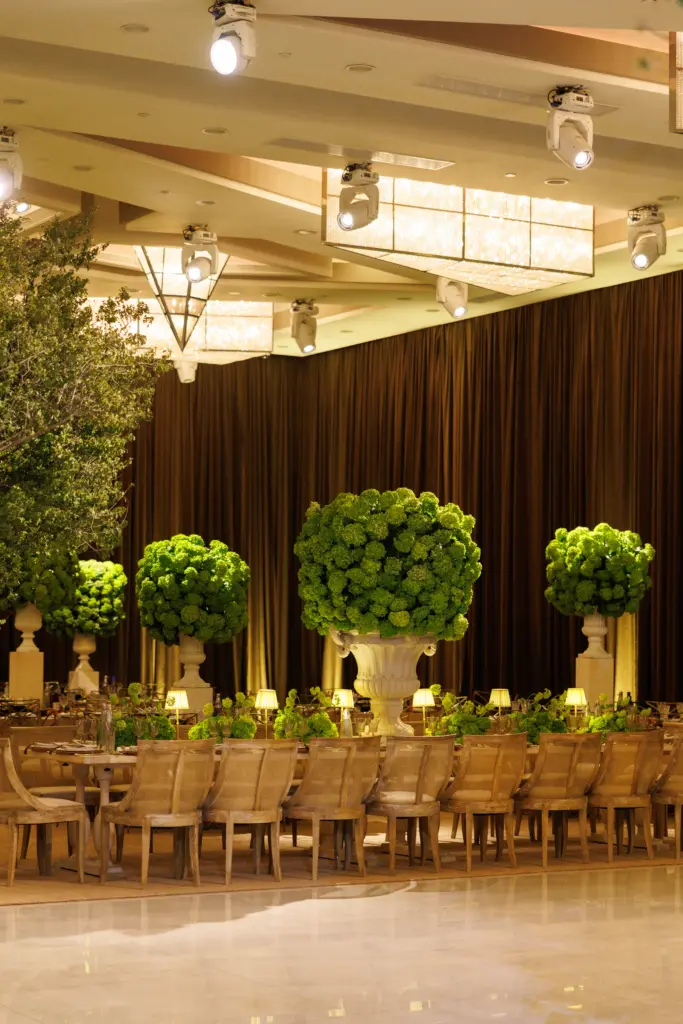 Long banquet tables set beneath tall topiary centerpieces in The Landmark ballroom