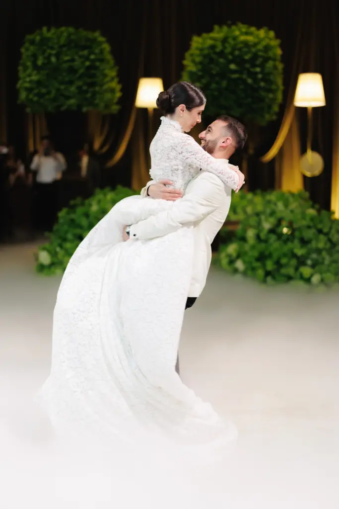 Groom lifting his bride as they embrace on the dance floor at their wedding reception