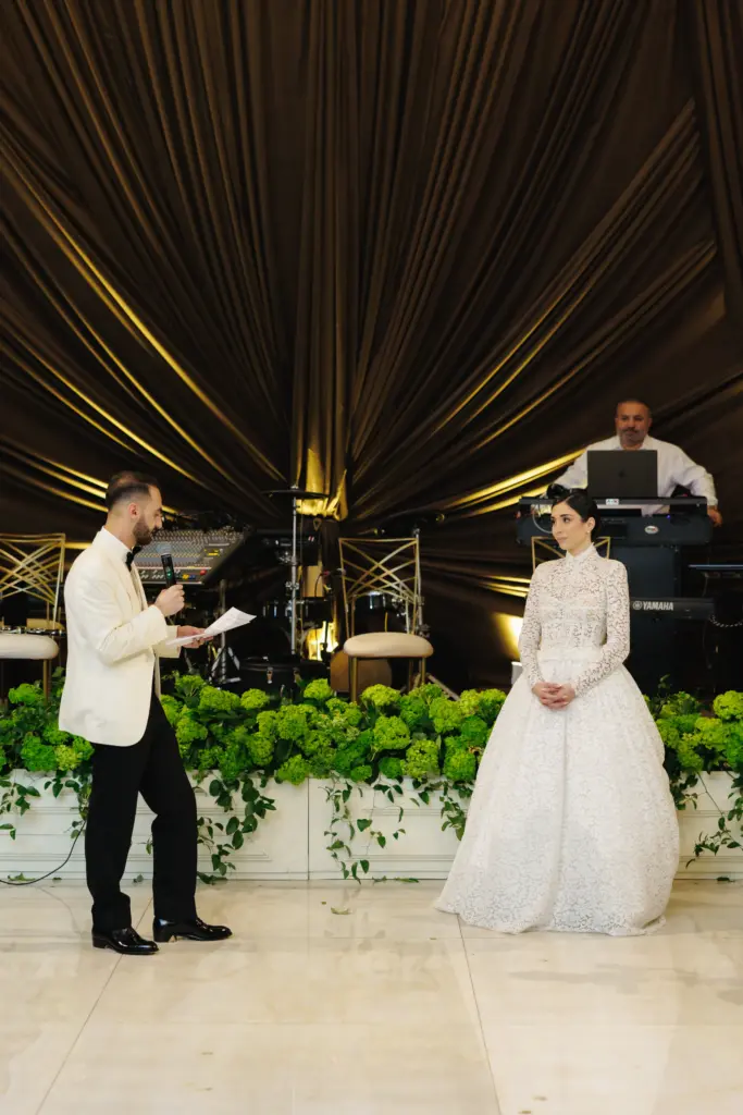 Emcee giving a toast on the microphone beside the bride during the reception