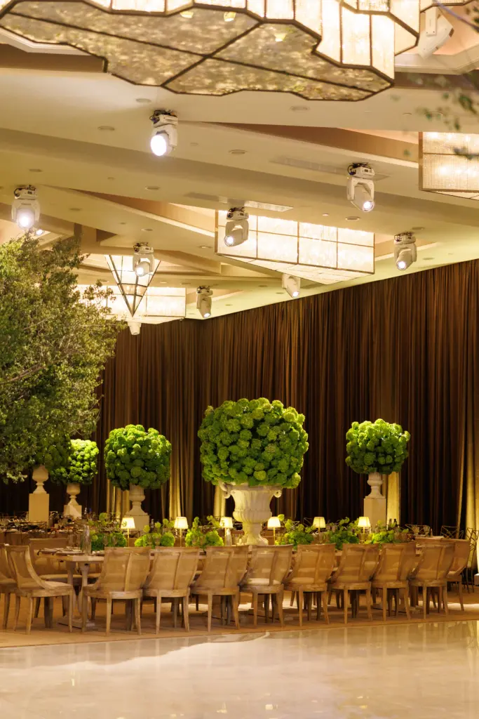 Ballroom reception set with topiary centerpieces and rows of wooden chairs at The Landmark