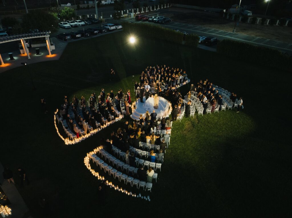 Aerial view of a couple exchanging vows at The Landmark, surrounded by guests and candlelit pathways at dusk