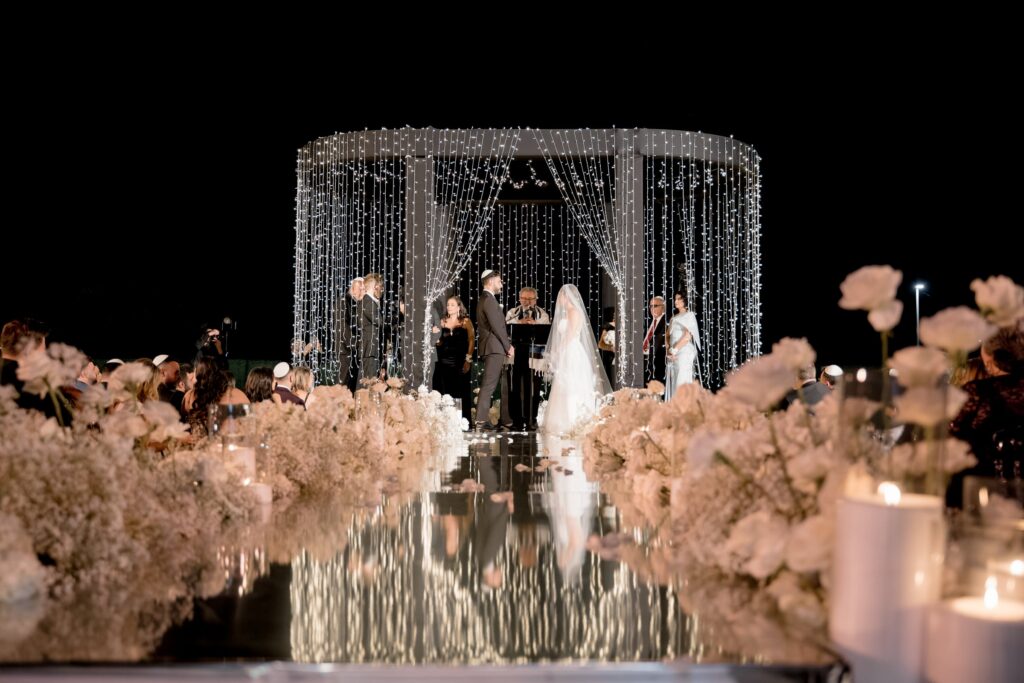 Aerial view of an empty ceremony aisle beneath a white pergola with rows of chairs at The Landmark