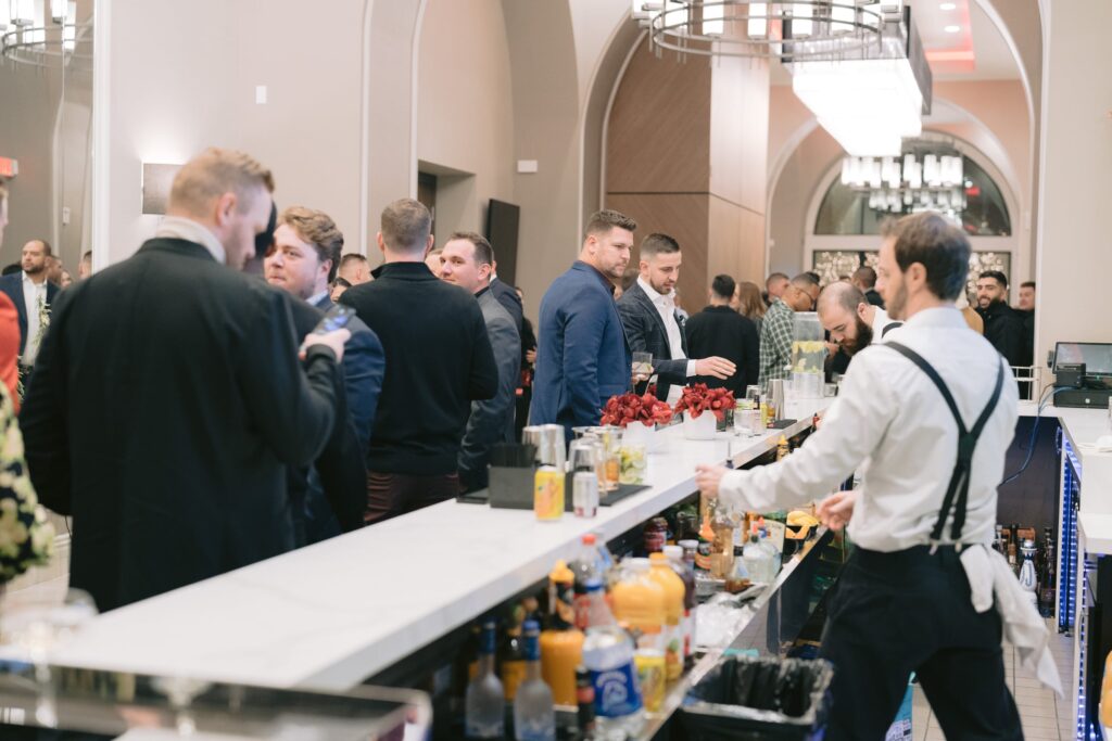 Bartender serving cocktails to guests at a busy reception bar