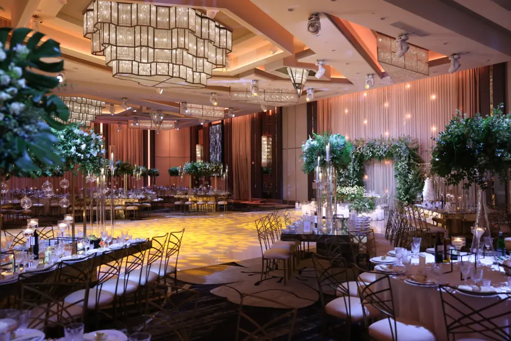 Reception ballroom with tall greenery centerpieces and a gold dance floor at The Landmark