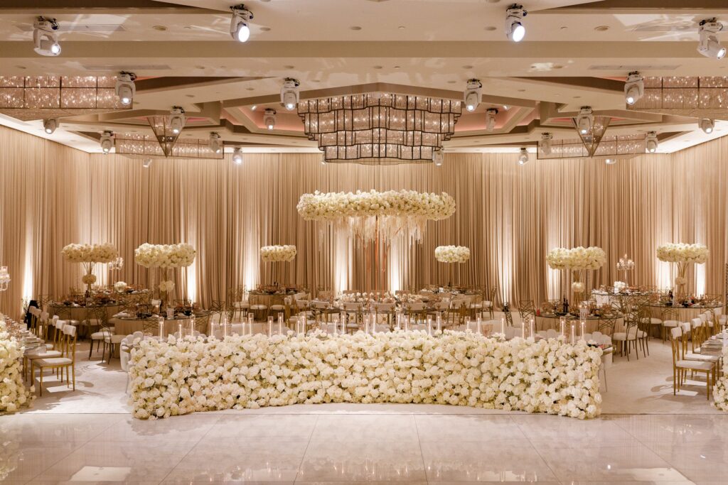 Elegant reception ballroom with a floating white floral installation and a flower-covered head table