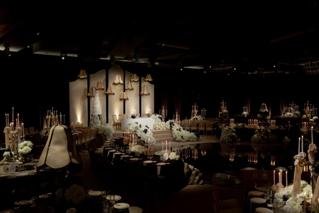 Candlelit ballroom reception with a floral sweetheart stage and reflective dance floor at The Landmark