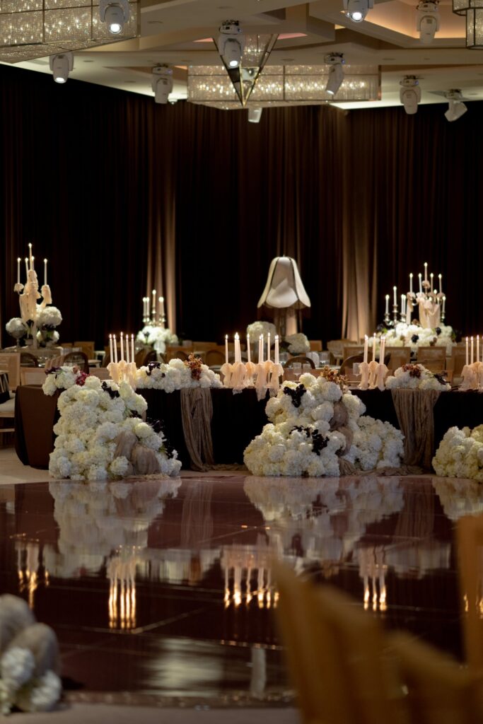 Close-up of white and black floral centerpiece clusters with tall candles on reception tables