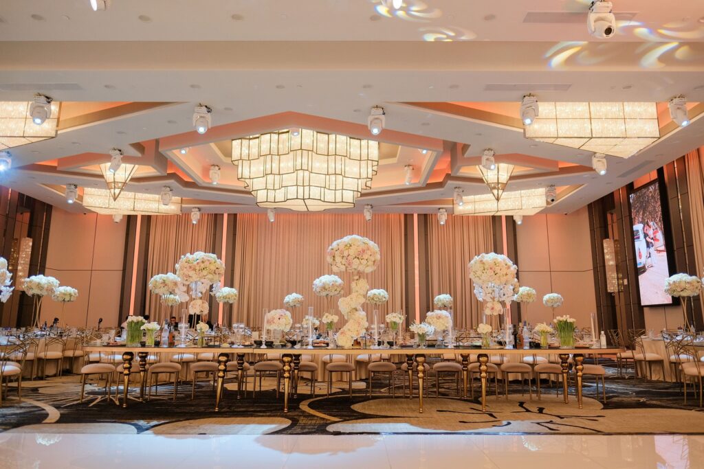 Banquet hall with U-shaped guest tables and tall white and blush floral centerpieces