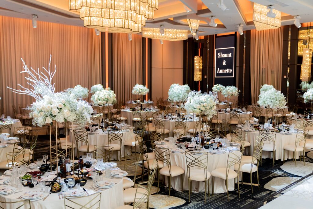 Reception tables with white branch centerpieces beneath a Shaunt and Annette welcome sign