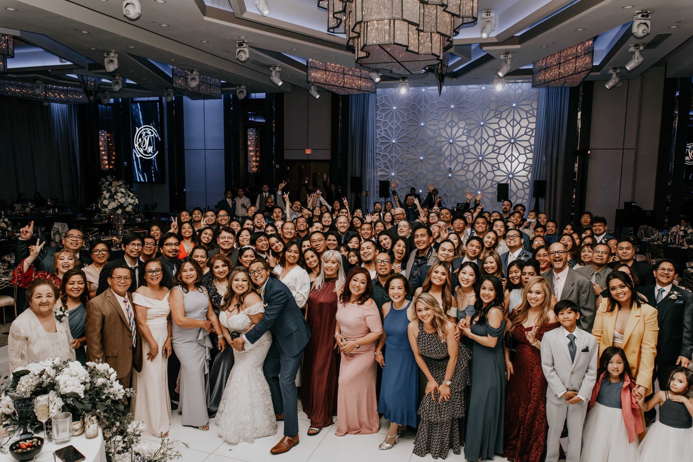 Large wedding party and family group photo posed in a ballroom reception hall