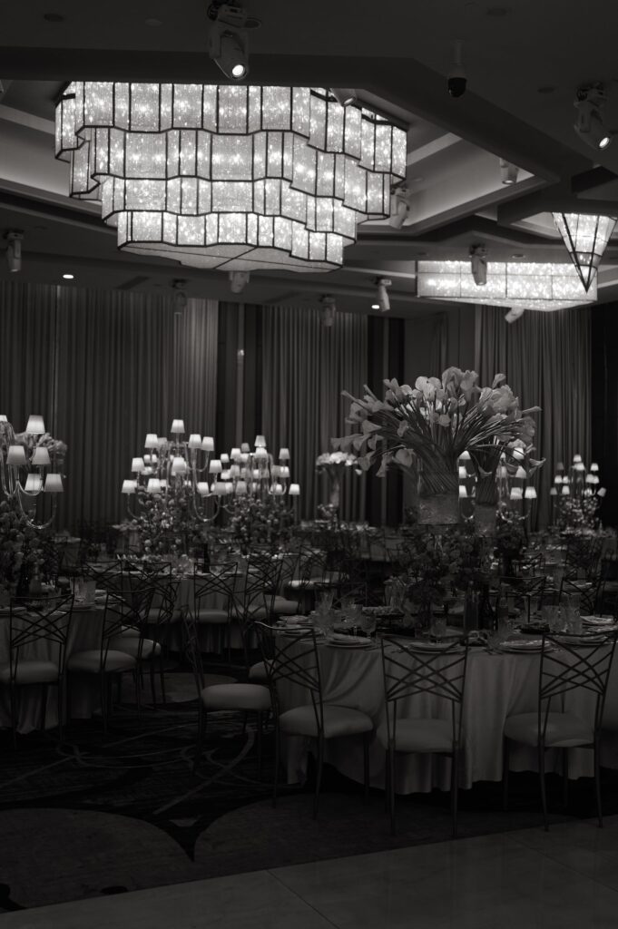 Black-and-white photo of candlelit reception tables with tall calla lily centerpieces