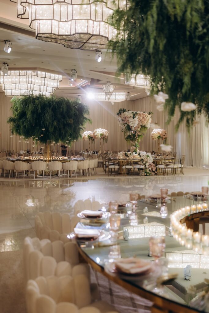 Reception with a hanging green willow-style floral centerpiece over round guest tables