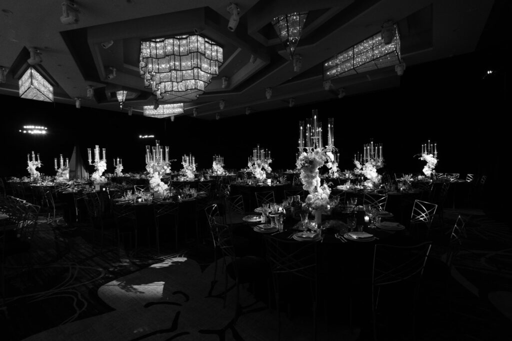 Formal ballroom set with candlelit floral centerpieces and crystal chandeliers