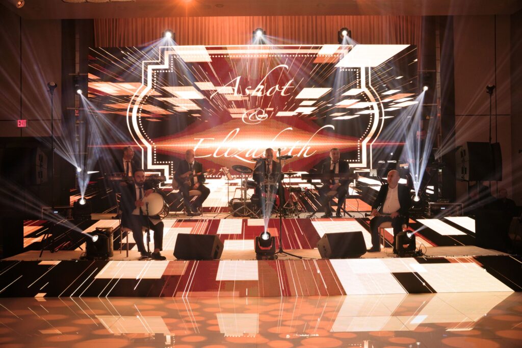 Live band performing on a lit stage with a couple's name displayed behind them