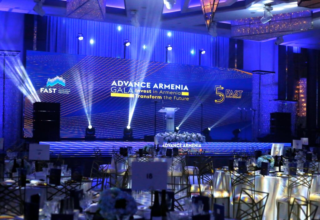Ballroom set with a blue-lit Advance Armenia Gala stage backdrop