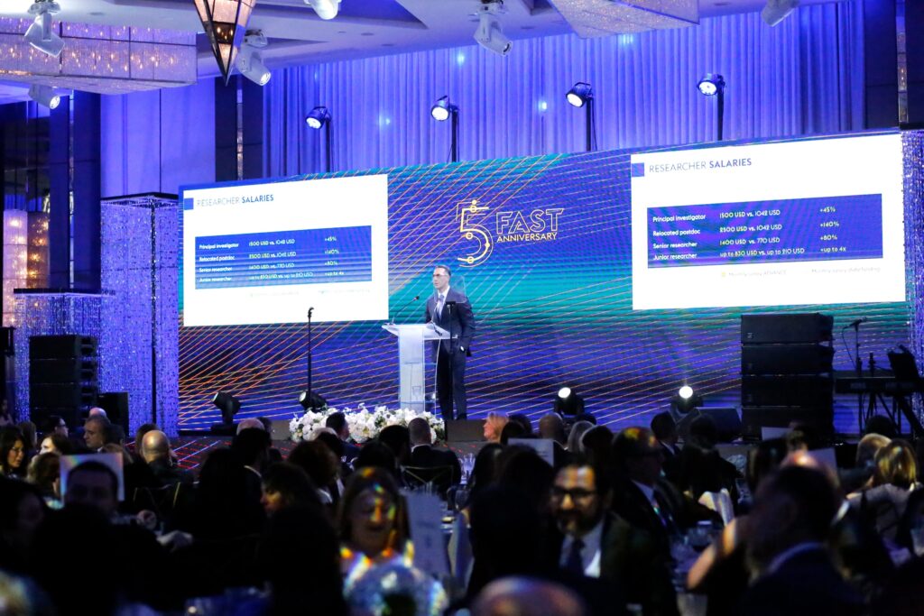 Speaker presenting data slides on screen at a corporate gala event