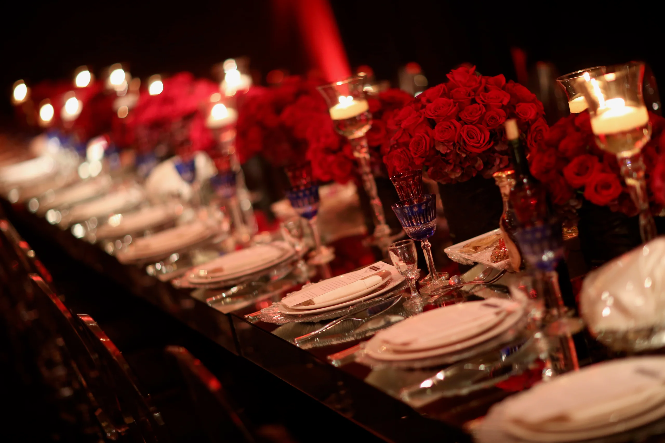 Elegant banquet table with red rose arrangements and lit candles