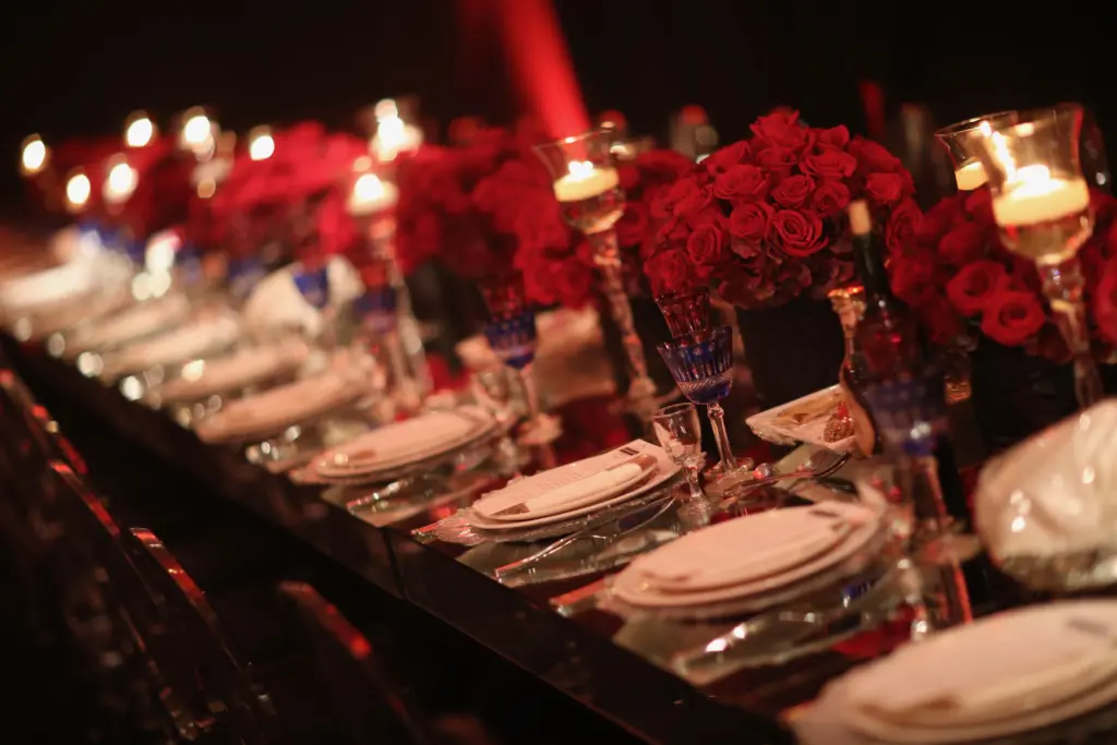 Banquet table lined with red roses, candles and place settings