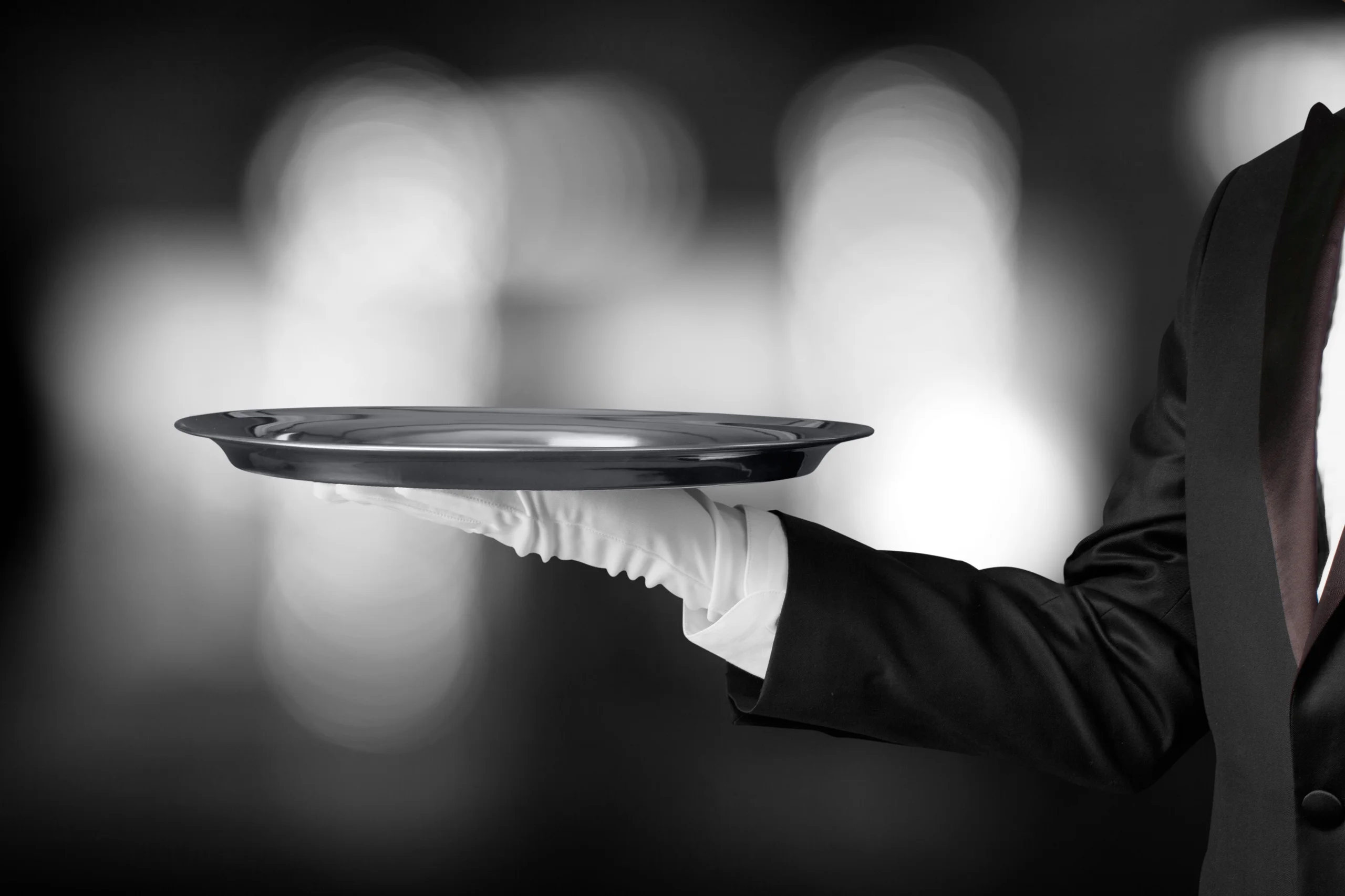 Waiter in white gloves holding an empty silver serving tray