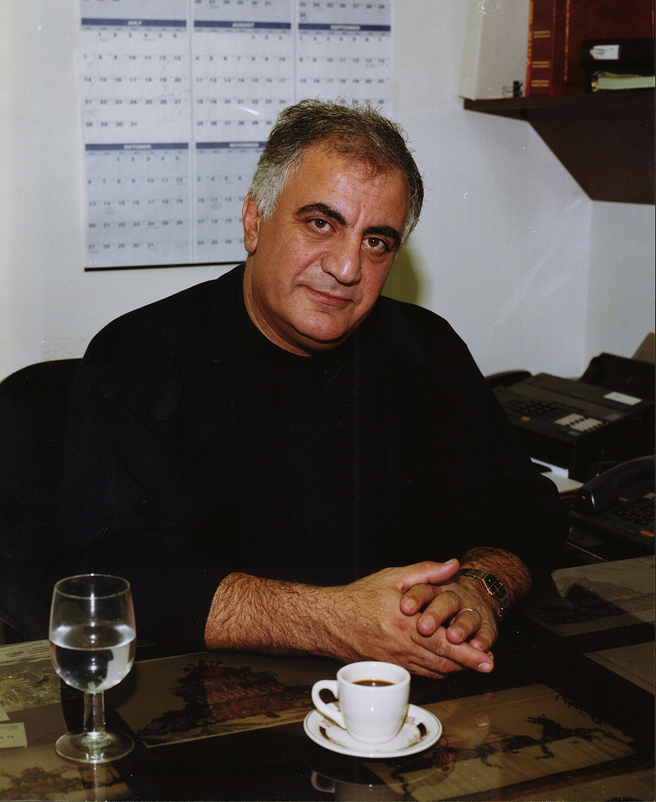 Portrait of a man seated at a desk with a cup of coffee