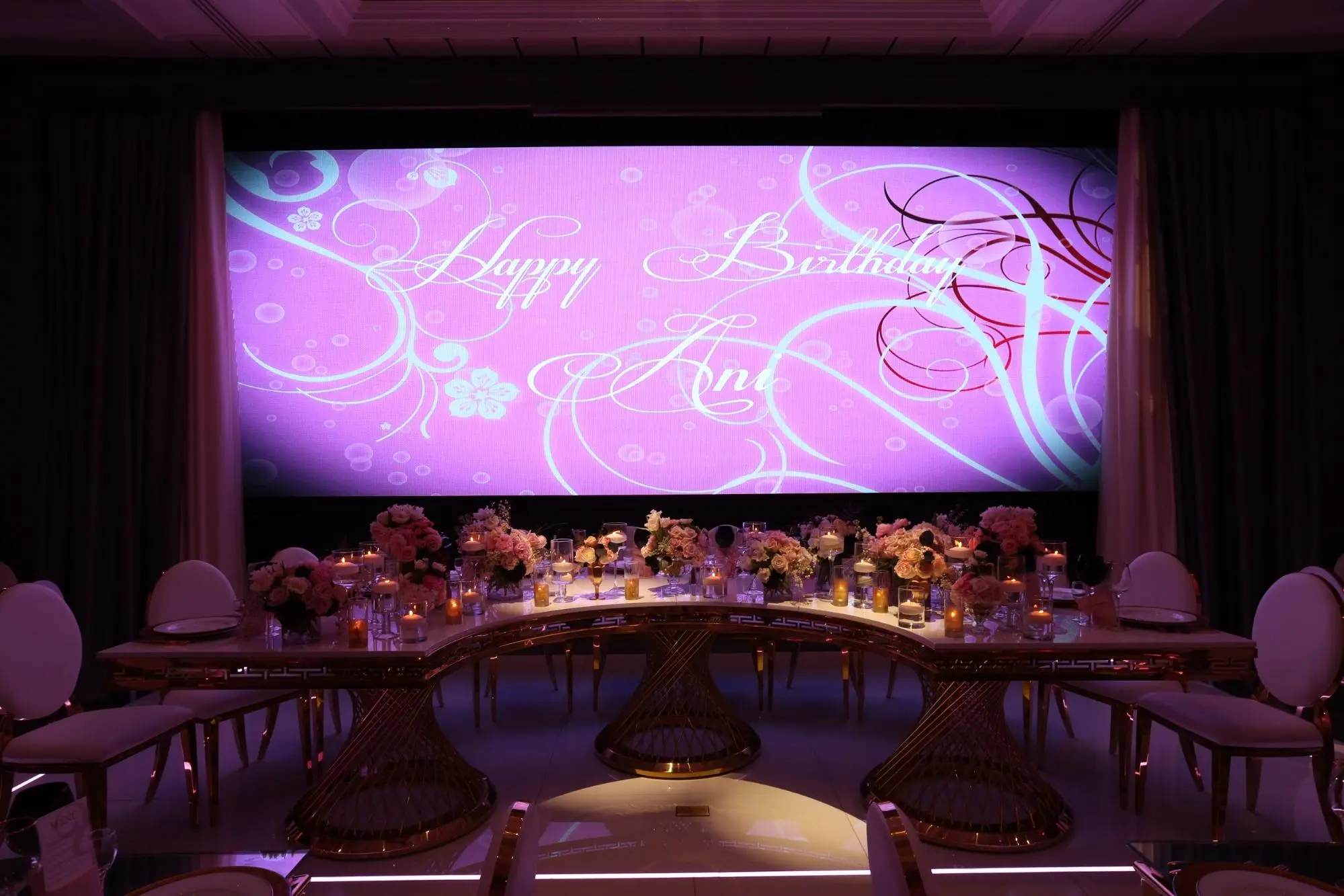 Happy Birthday backdrop with a round table set in pink and gold florals