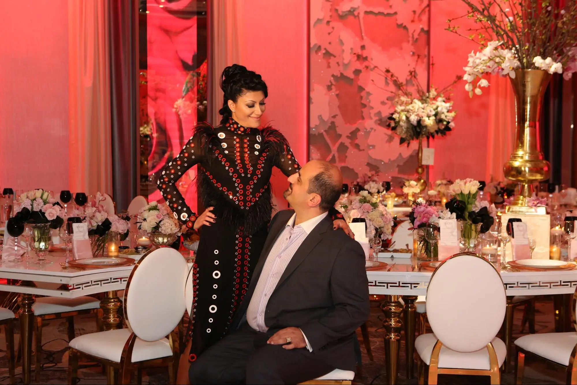 Wedding guests laughing together at a pink-lit reception table